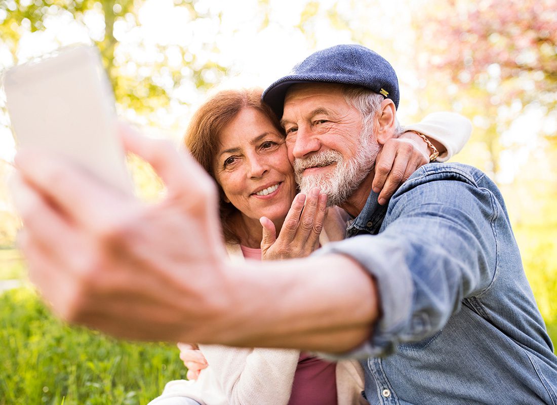 Medicare - Elderly Couple Embrace Each Other as They Take a Selfie on a Sunny Day